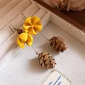 Close-up of handmade forest style earrings with yellow wooden flowers and pine cones. - Hazelnut Pendant Style (HE33613) / Yellow