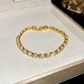 Primo piano di un bracciale tennis placcato oro 18 carats con zirconi in una scatola - Oro