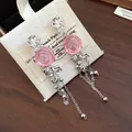 Close-up of pink resin rose tassel earrings on a linen jewelry pouch - Resin Wrinkled Flower Tassel (HE33052) / Pink