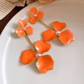 Detailansicht von leuchtend orangefarbenen Emaille-Ohrringen mit eleganten Perlenmitten - Stahlnadel-Stil / Orange