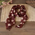 Dettaglio di sciarpa in chiffon floreale bordeaux su un tavolo in legno naturale - Fiore Caffè
