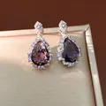 Close-up of elegant purple teardrop zircon earrings on a champagne jewelry box - Earrings / Purple
