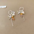 Vue détaillée d'élégantes boucles d'oreilles hirondelle en argent avec perles - Créoles (Corps Ton Argent) / Café