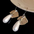 Close-up view of elegant silver teardrop pearl earrings with unique golden mesh detail - Silver