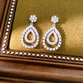 Nahaufnahme von tropfenförmigen Ohrringen mit schimmerndem Zirkonia-Pavé-Besatz. - Silber