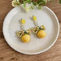 Close-up of yellow rose bud earrings with intricate beaded tassels on a plate - Silver Earring Post Style / Yellow