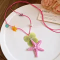 Detailed view of pink cord necklace featuring a large starfish and floral charms for beach vacation - Pink-Green