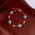 Close-up of a gold bracelet with turquoise four-leaf clover charms on brown fabric - No 7 Classic Four-Leaf Clover Style