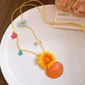 Detailed macro view of a sunset bay necklace featuring starfish, seashell, and flowers - Yellow-Orange