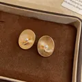 Detailed view of vintage oval textured gold stud earrings with a central pearl - Alloy Gold color (18k Gold Plated, Silver post)