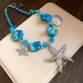 Nahaufnahme einer Meereshalskette mit blauen Glasperlen und silbernen Seesternen. - Blau