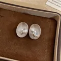 Close-up macro view of vintage style oval textured stud earrings with a central white pearl - Alloy Silver color (Silver post)