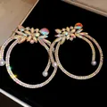 Close-up detail of oversized crystal hoop earrings with iridescent floral stones and pearls - Teardrop Pearl Pendant / Gold