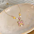 Detail of a gold necklace featuring a colorful oil-dripping butterfly and flower pendant. - Necklace / Gold-Pink-Yellow