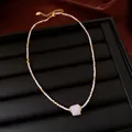 Close-up of white seed beads and a square pink stone pendant on a gold necklace - Gold-White-Pink