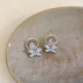 Nahaufnahme von eleganten Schmetterling-Ohrsteckern mit hellblauen Zirkonia und Silberstiften - Schmetterling Design / Blau