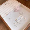 Détail d'un collier de perles avec fleur en mousseline rose dans un plateau de bijoux - Collier Fleur en Chiffon et Perles / Blanc-Rose