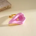 Primer plano de anillo de flor de cala en esmalte rosa con detalle de pistilo dorado - Rosa
