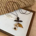 Close-up of Bohemian retro sweater chain with amber leaf pendant and wooden beads - 2# Brown Necklace