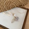 Close-up of Bohemian heart and leaf pendant necklace displayed on rustic wooden backdrop - 4# Necklace - White