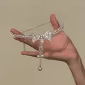 Primo piano dettagliato di un ciondolo a fiocco scintillante con perle e nappine eleganti - Collana choker / Argento