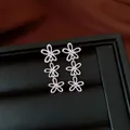 Close-up detail of silver-colored tiered hollow flower earrings on black display tray. - Hollow Three-Flower Linked Style / Silver