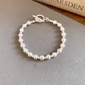 Close-up of elegant silver-toned beaded bracelet with textured finish and toggle clasp. - Bracelet / Silver