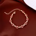 Elegant gold bracelet featuring oval red gemstones and sparkling white crystals on dark fabric. - No 52 Gold Red Zirconia Style