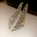 Gros plan de boucles d'oreilles à pampilles en strass étincelantes et brillantes - Or