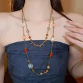 Detailed view of a handmade stackable beaded necklace with crystal and flower charms on model - Bohemian Layered Style(HN8756) / 4# Necklace-Gold-Red-Coffee