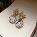 Detailed shot of gold butterfly earrings with floral rhinestone sphere pendants - Butterfly Flower Pearl Stud Earrings (HE33405) / Gold-Multicolor