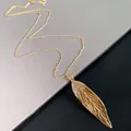 Detailed close-up showing a gold-colored leaf pendant necklace with elegant rhinestone accents - Necklace / Gold