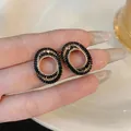 Close-up view of elegant oval black zircon stud earrings with premium hollow design details - Black & Gold