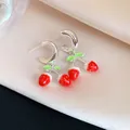 Vista macro de pendientes de fresa de esmalte con ganchos de aguja de plata finos - Forma de fresa / Rojo y Verde