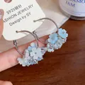 Dettaglio di orecchini a cerchio in argento decorati con fiori di resina bianchi e blu - Cerchio in argento (HE32040) / Blu