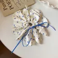 Detailed close-up of a white silk scrunchie with blue floral pattern and ribbon - White/Blue