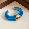 Nahaufnahme eines blauen transparenten Harz-Armreifs mit goldenem Muschel-Detail - Blau