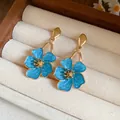 Elegant blue floral enamel drop earrings displayed in a soft cream velvet jewelry box - Blue