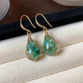 Elegant close-up of teardrop resin earrings featuring green dried flowers and gold hooks. - Hook Earring (HE31705) / Gold-Green