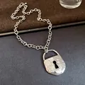 Detailed macro shot of a retro silver-colored metal chain necklace with lock pendant. - Lock Shape / Silver