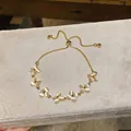 Detailed view of an adjustable gold bracelet featuring elegant cat-eye stone flower charms - Four-petal Flower Style