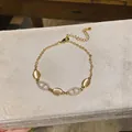 Macro detail of elegant gold bracelet featuring cat eye stones and pavé zircon oval links - Oval Anchor Chain Style
