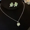 Close-up of elegant four-leaf clover cat's eye stone jewelry set on black display - Necklace and Earrings Set / Green