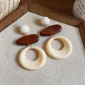 Dettaglio macro di orecchini vintage con elementi in legno marrone e cerchi in resina crema - Ago in Argento-Bianco-Caffè
