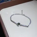 Macro view of vintage silver bracelet with sparkling zircons and green center stone - Silver/Green
