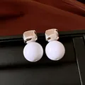 Detalle macro de pendientes de tuerca retro cuadrados plateados y esferas de resina blanca - Estilo de poste de pendiente de plata / Plateado y Blanco