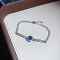 Close-up of a sparkling silver tennis bracelet featuring a central blue zircon with halo - Silver Aqua Blue