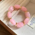 Close-up of pink irregular acrylic beads and gold spacers on a jewelry tray - Pink