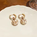 Dettaglio di orecchini a cerchio placcati oro 18k con ciondoli a sfera in occhio di gatto. - Oro