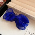 Detailed close-up of blue chiffon fabric flower dangle earrings in a beige jewelry box - Hook Style / Blue